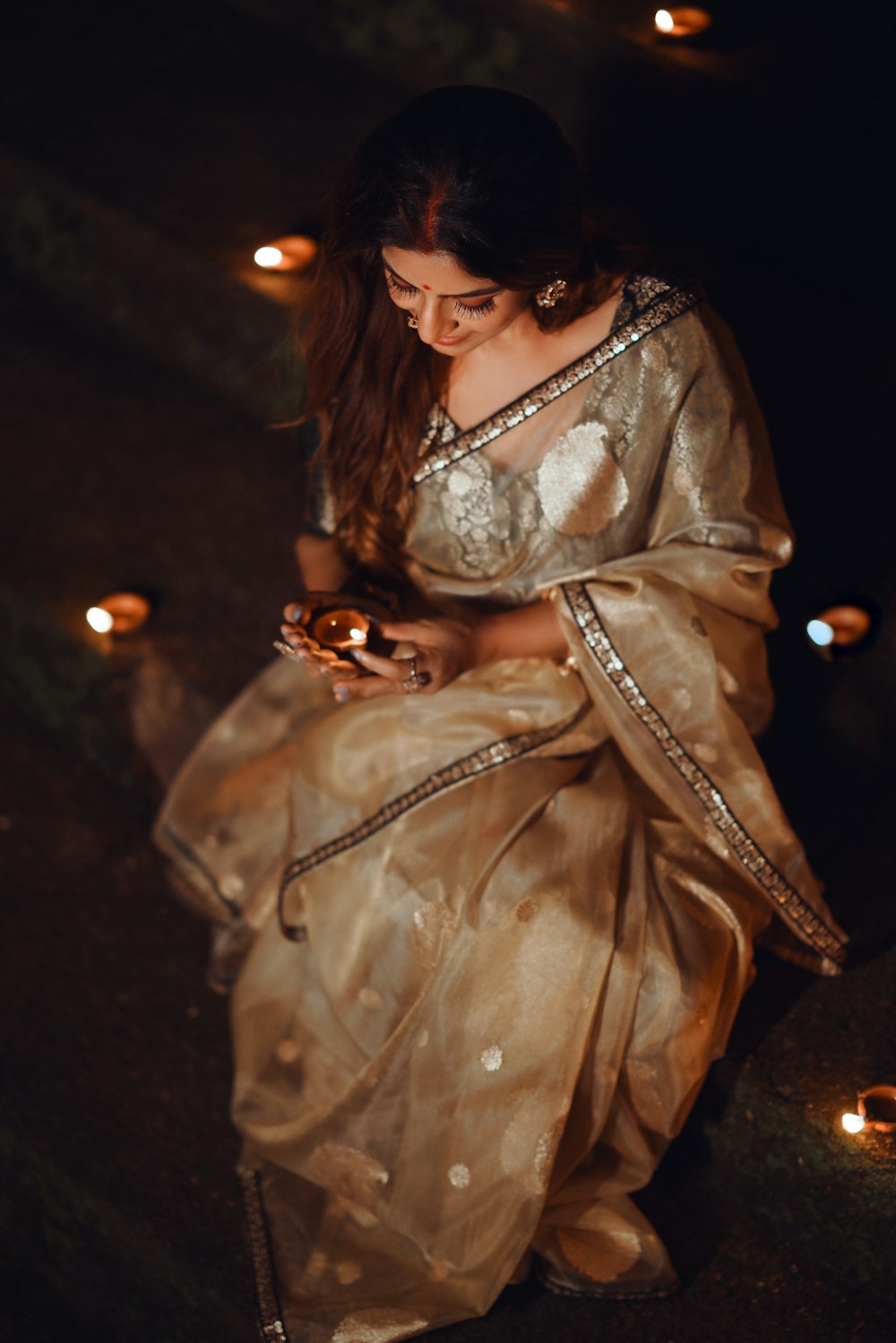 a woman in a gold sari sitting on the ground