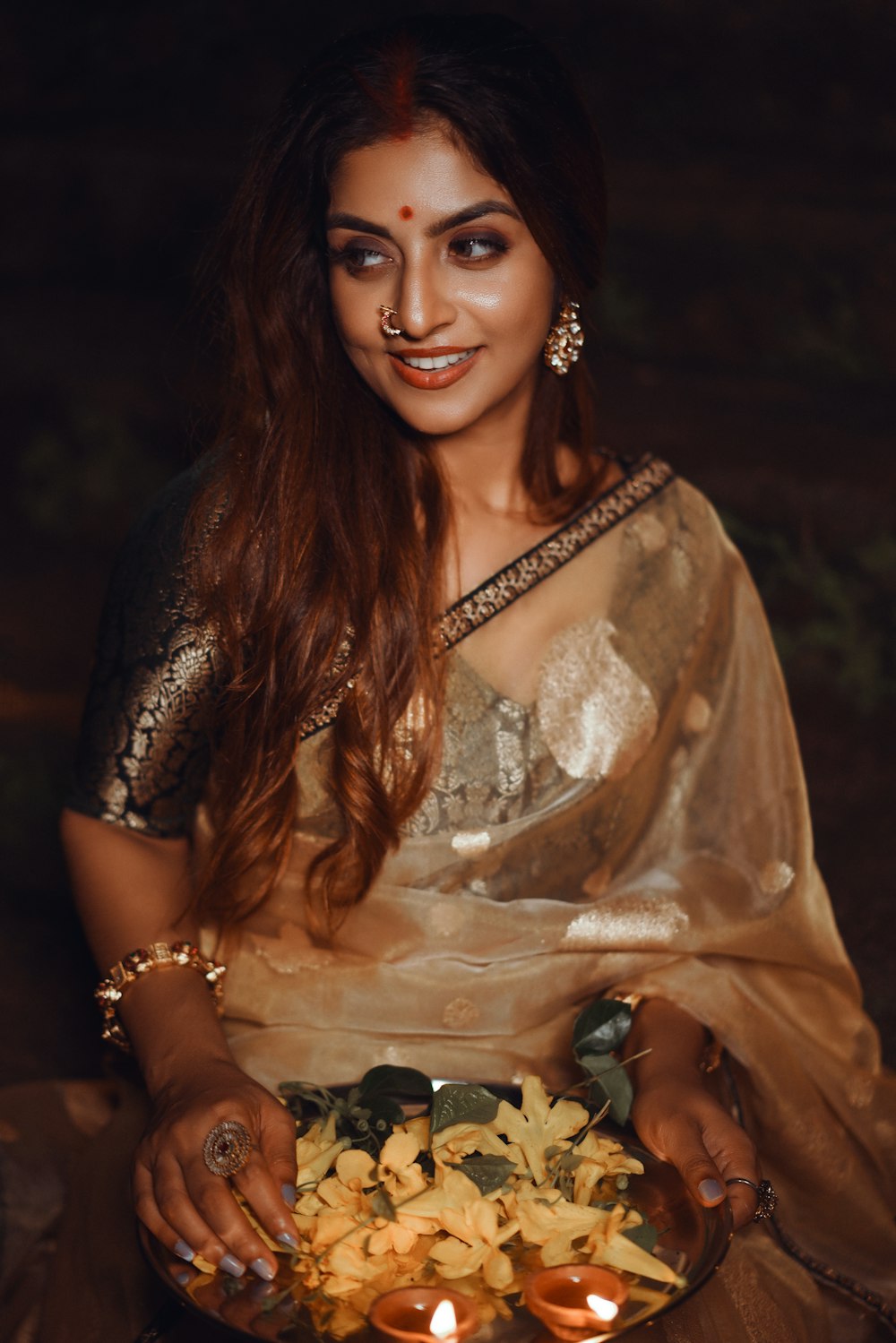 a woman in a sari holding a bowl of flowers