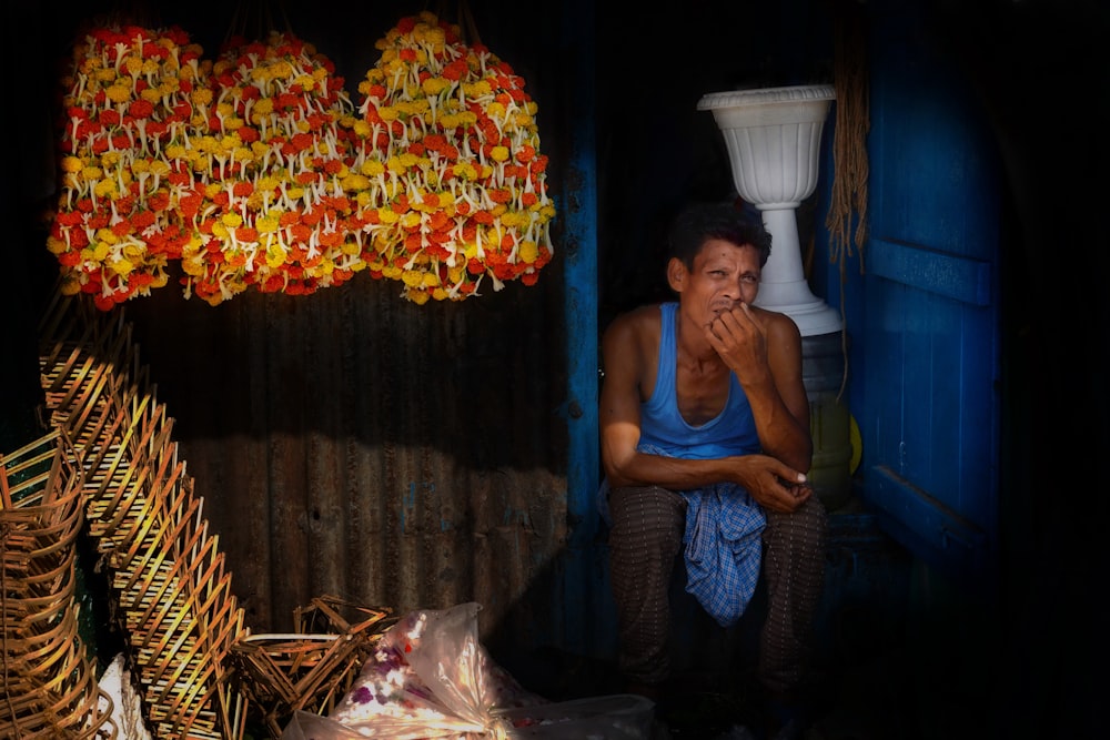 a man sitting in a doorway next to a bunch of fruit