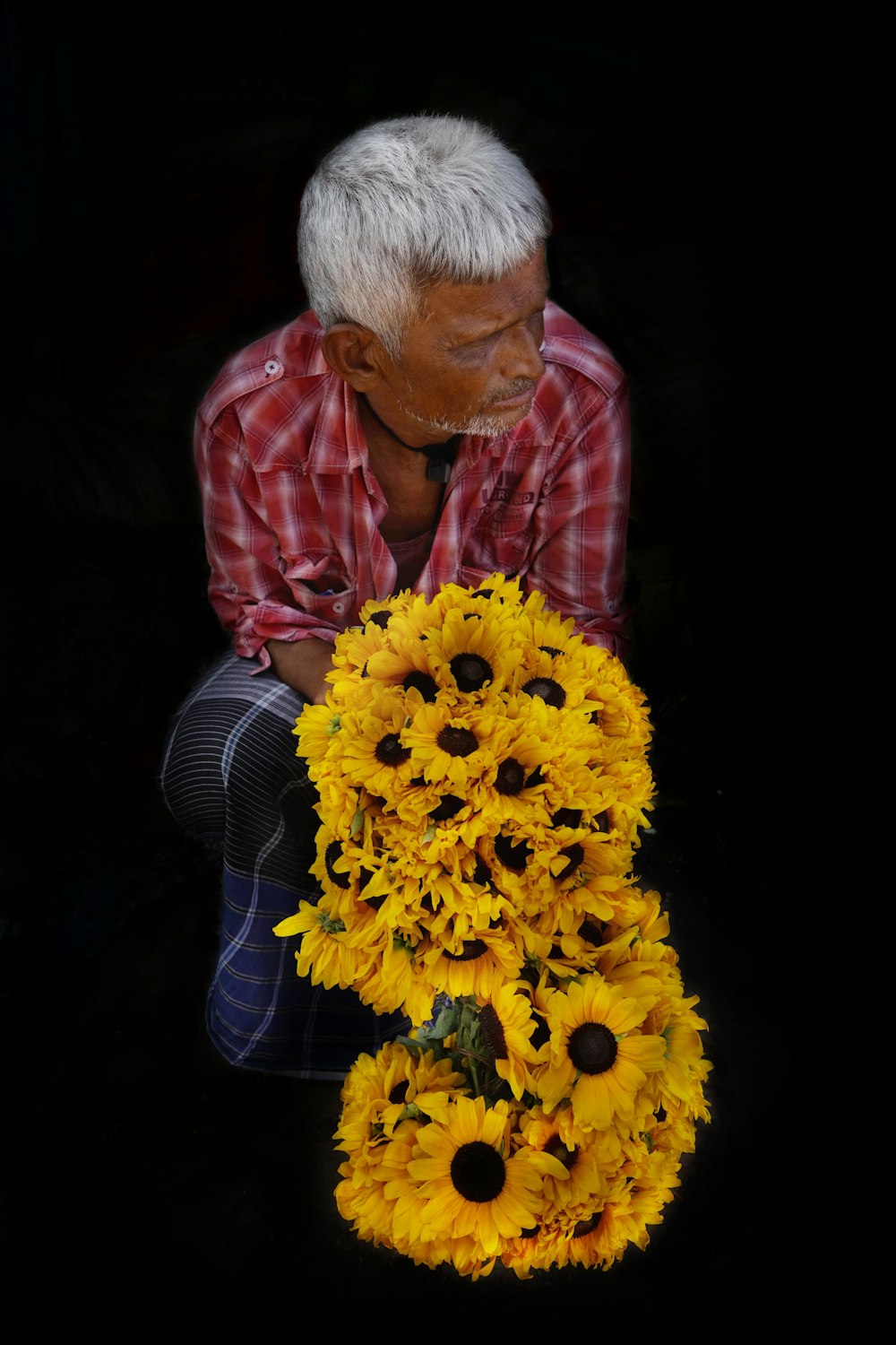 a man kneeling down with a bunch of sunflowers