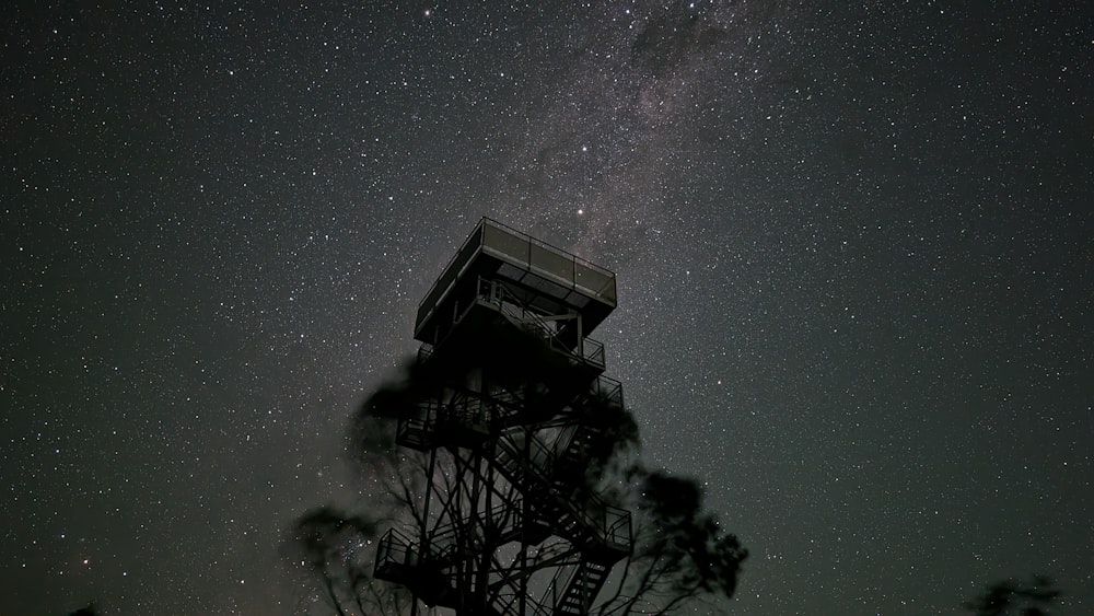 a tower that is under a night sky filled with stars