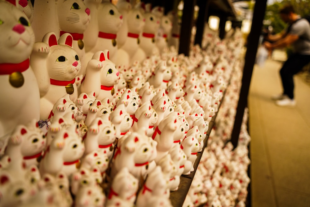 a bunch of white cat figurines sitting on a shelf