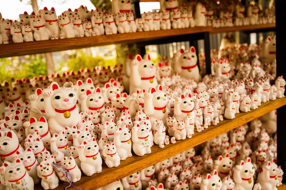 a shelf filled with lots of white cat figurines