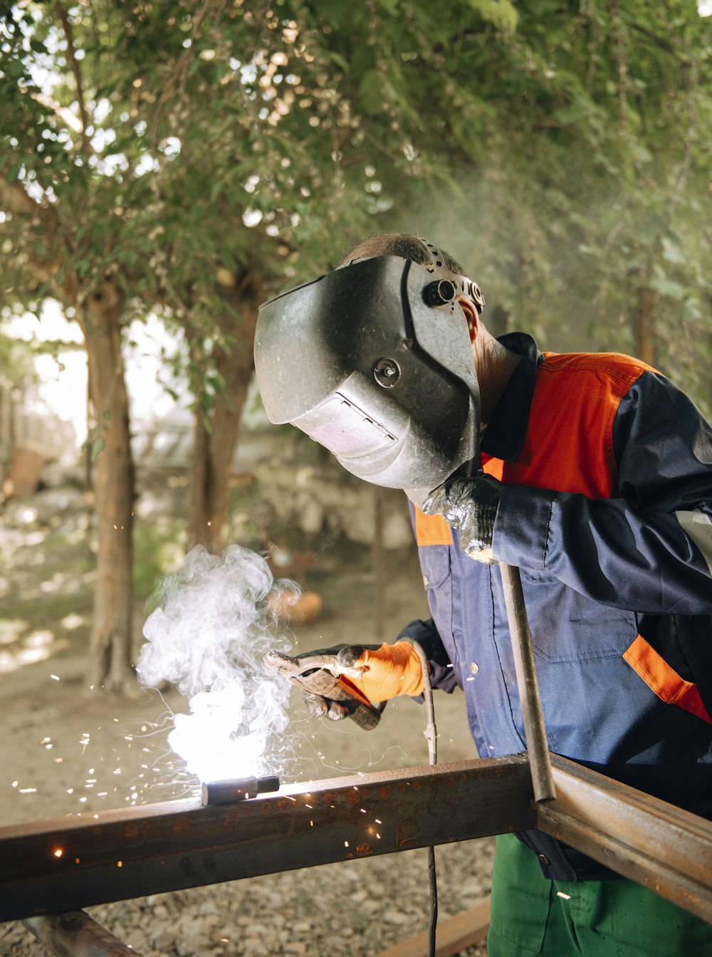 a man welding a piece of metal in a forest