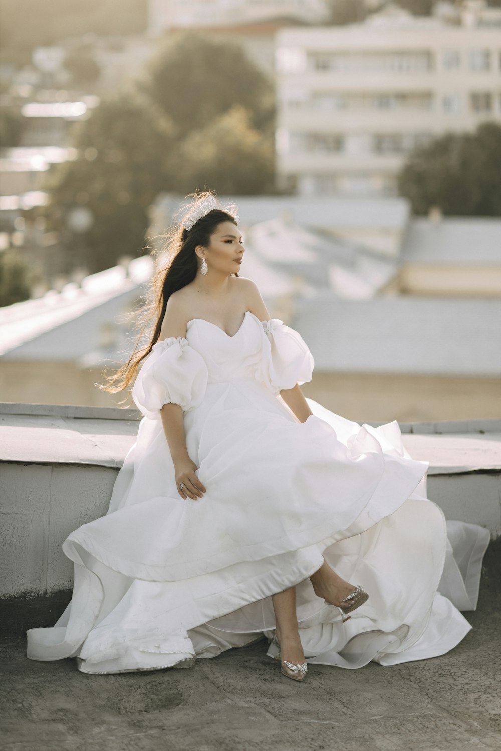 a woman in a white dress sitting on a ledge