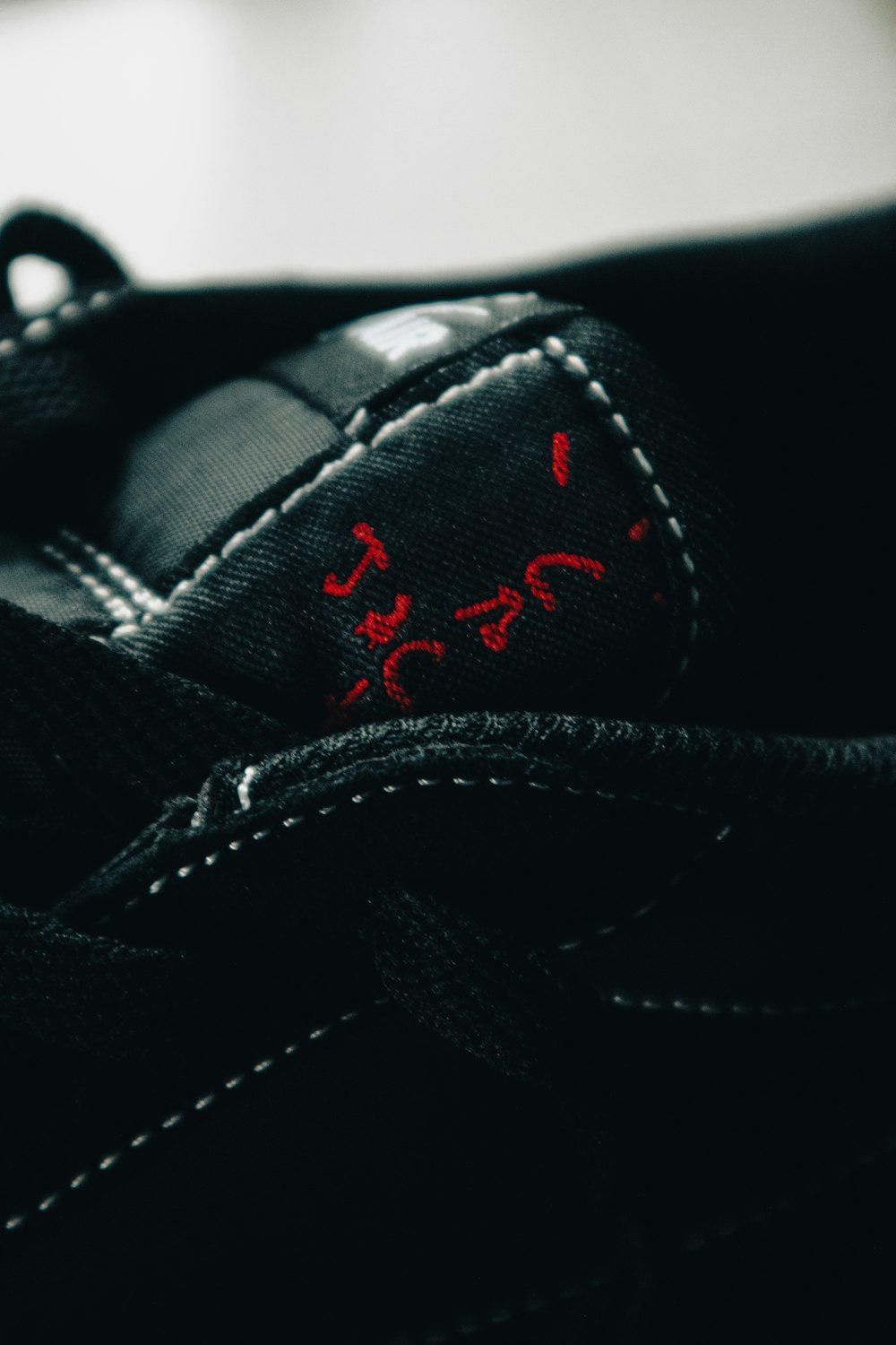 a pair of black shoes with red stitchs