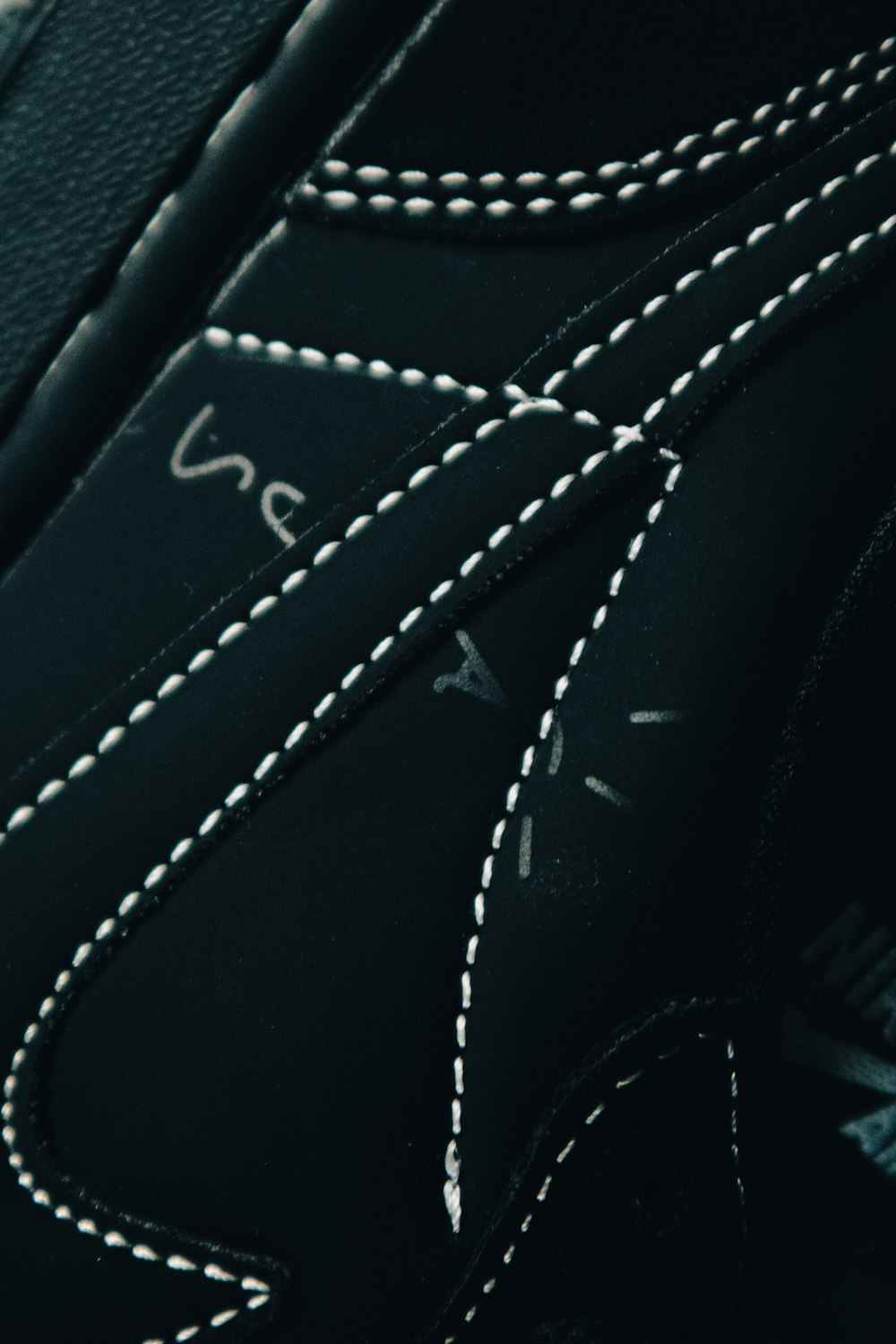 a close up of a black shoe with white stitching