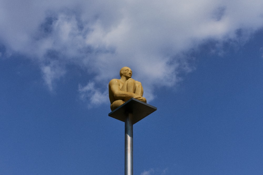 a statue of a man sitting on top of a pole