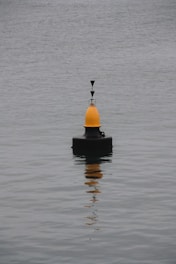 a yellow and black buoy floating on top of a body of water