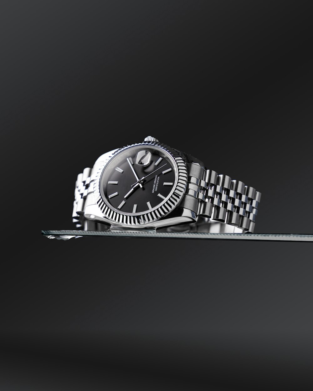 a rolex watch on a tray with a black background