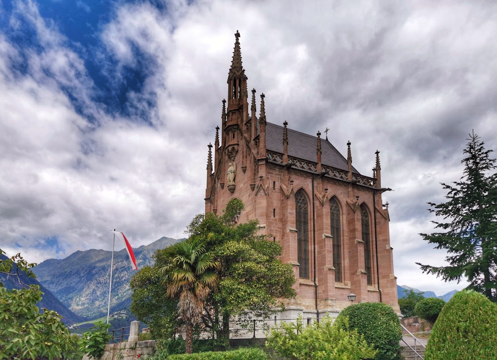 a church with a steeple surrounded by trees and bushes