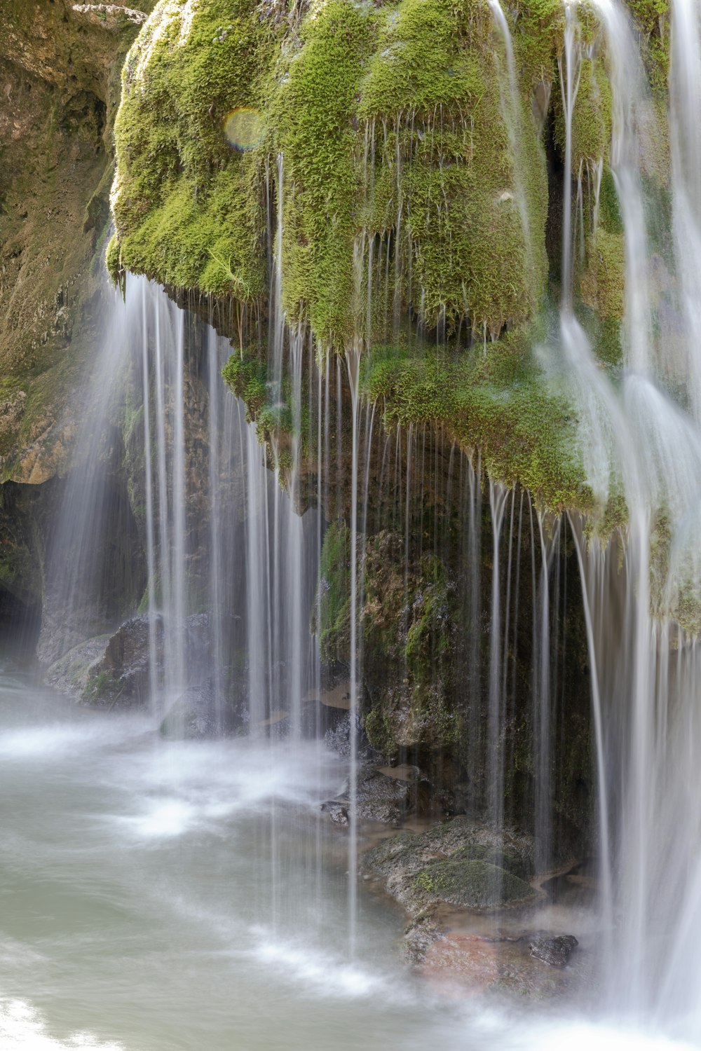 a waterfall with moss growing on the side of it