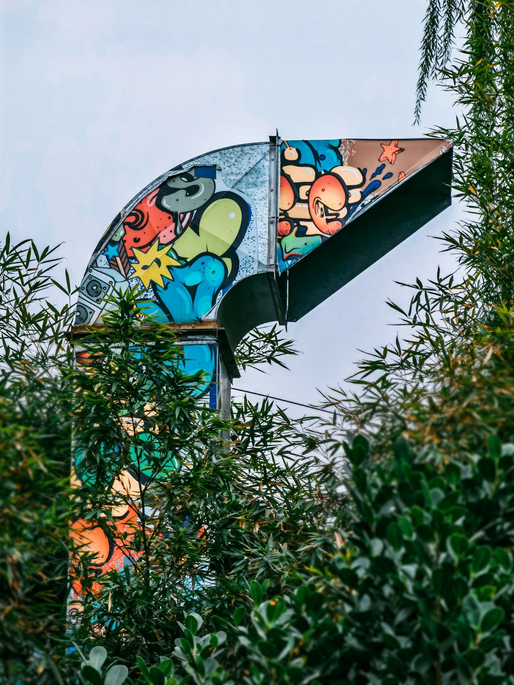 a colorful street sign with trees in the foreground