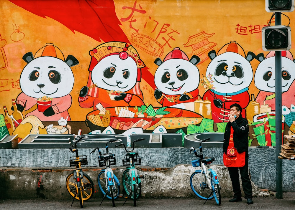 a woman standing in front of a mural of pandas