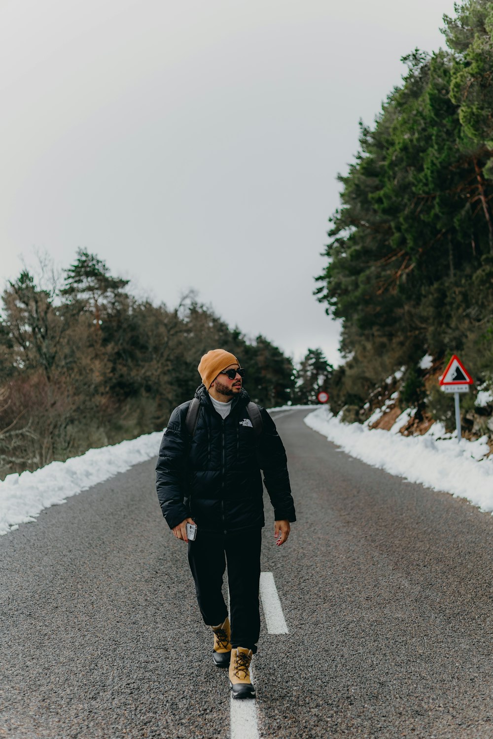 a man walking down a road in the snow
