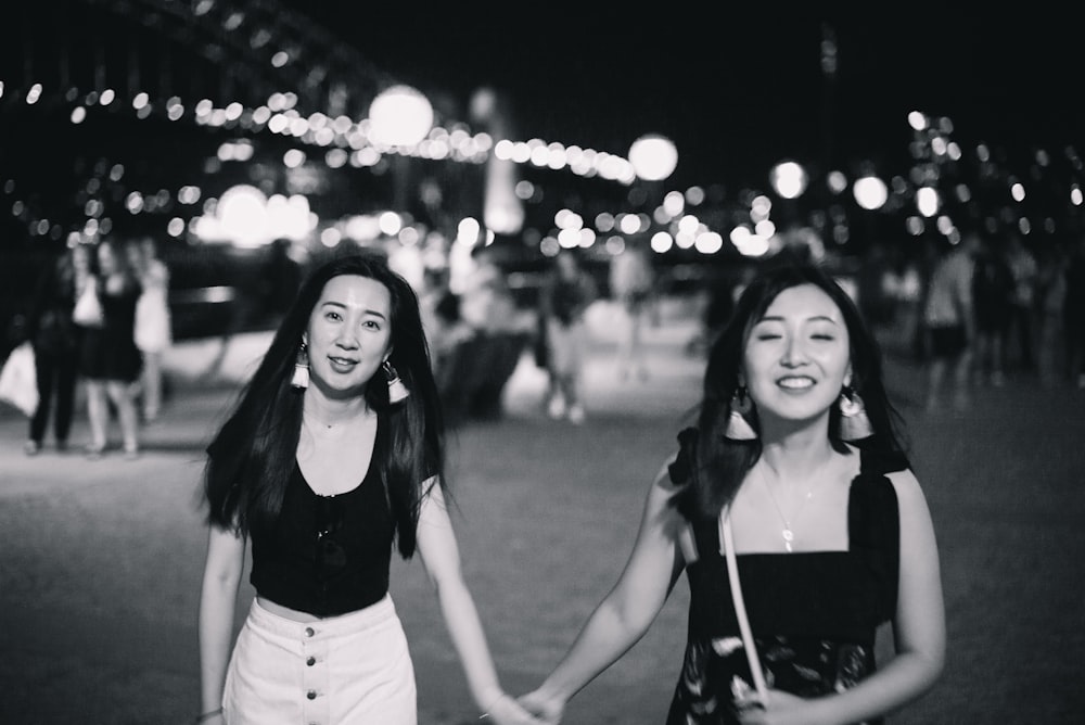 two young women holding hands in a park at night