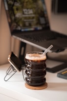 a cup of coffee sitting on top of a table next to a laptop