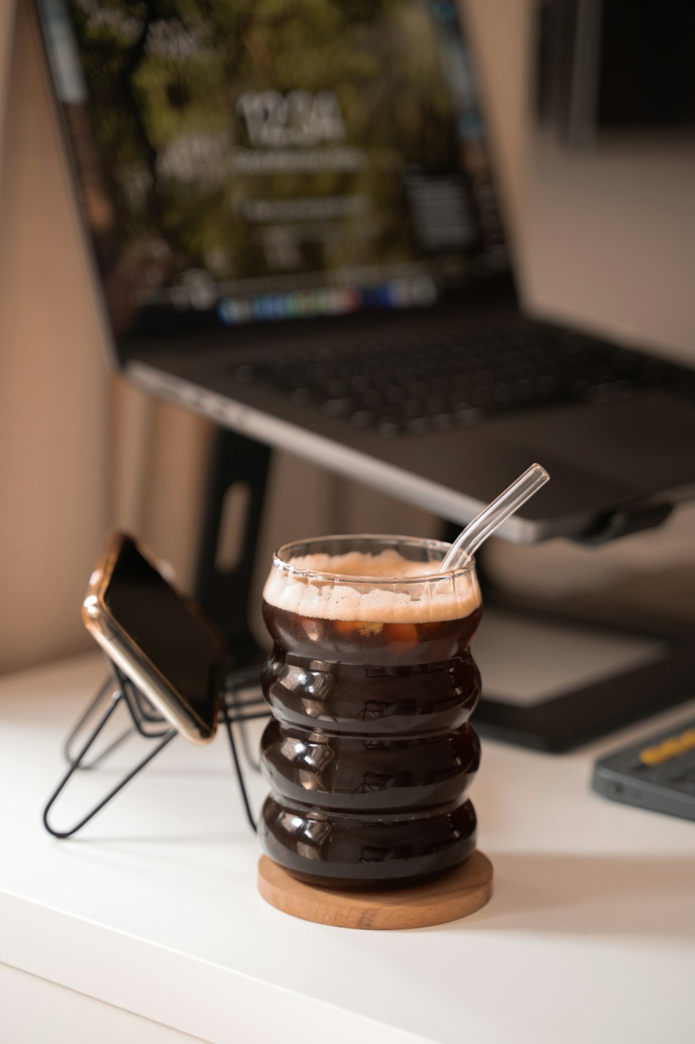 a cup of coffee sitting on top of a table next to a laptop