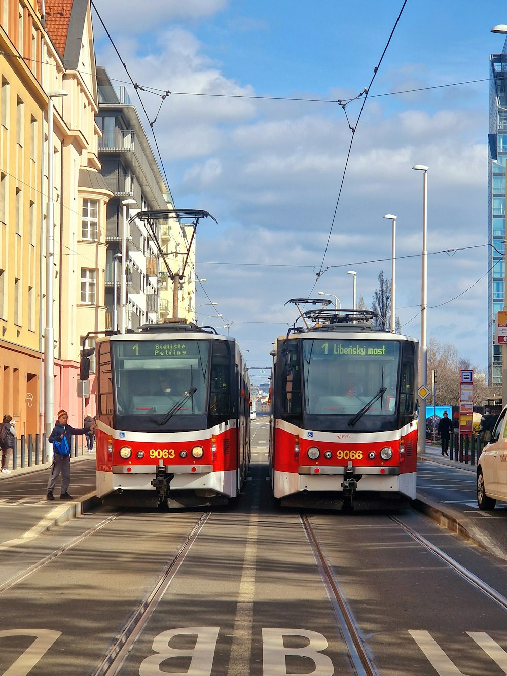 a couple of red and white trains traveling down a street