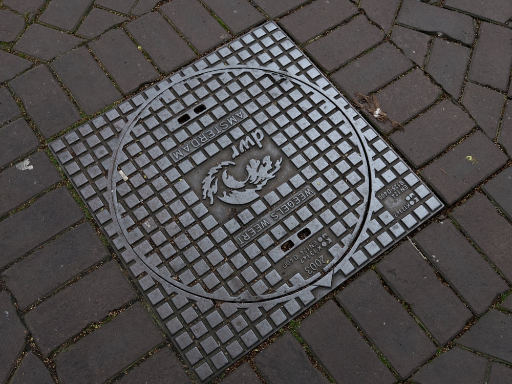 une plaque d’égout sur un trottoir en brique