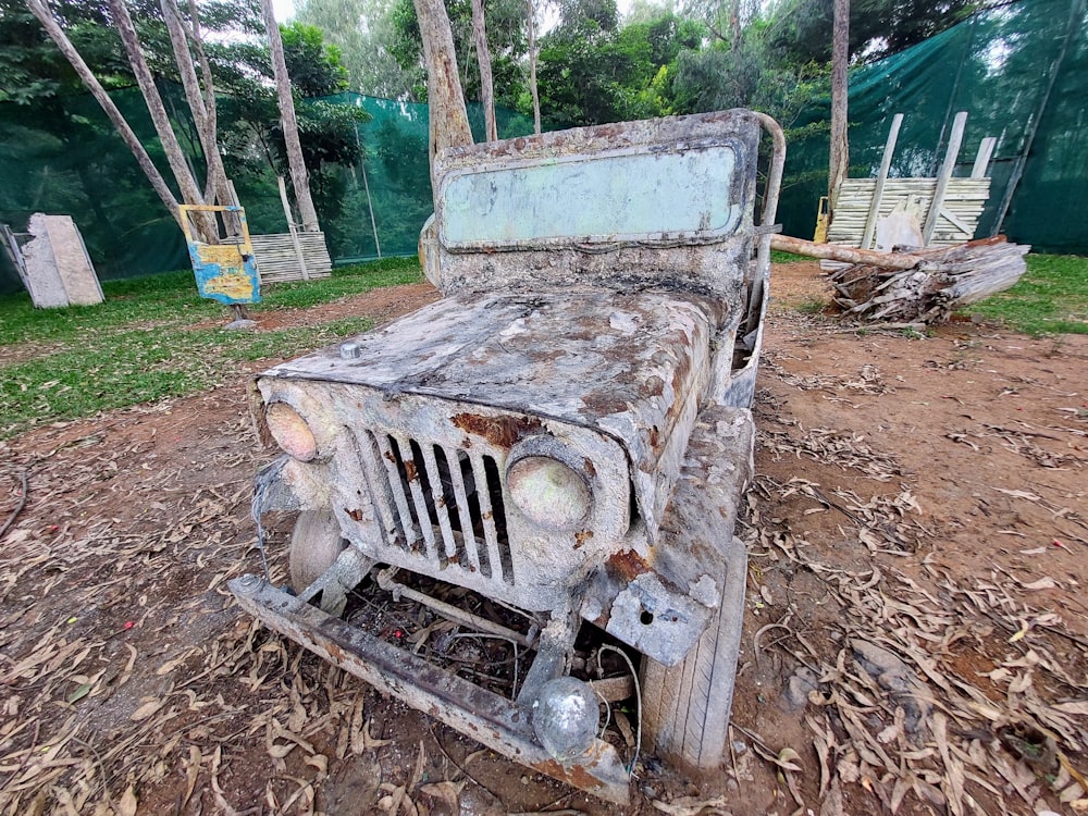 an old rusty jeep is sitting in the dirt