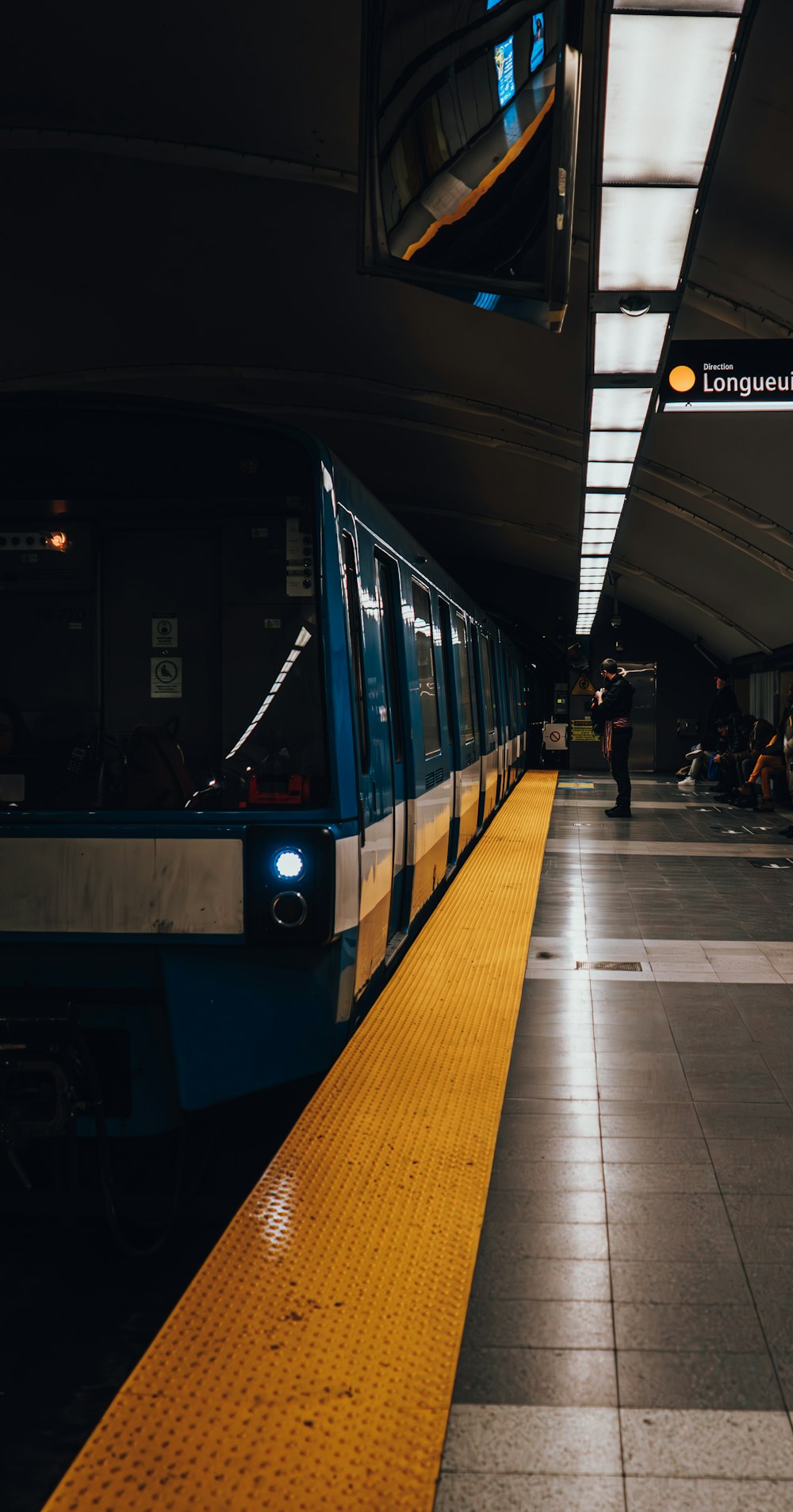 a blue and yellow train pulling into a train station