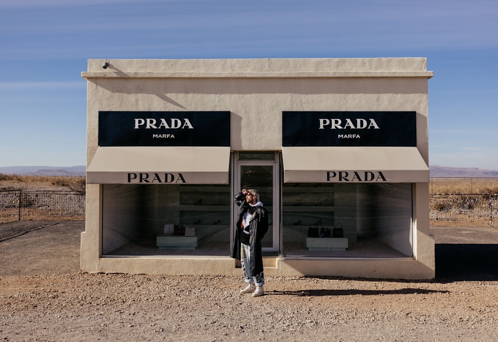 a woman standing in front of a prada store