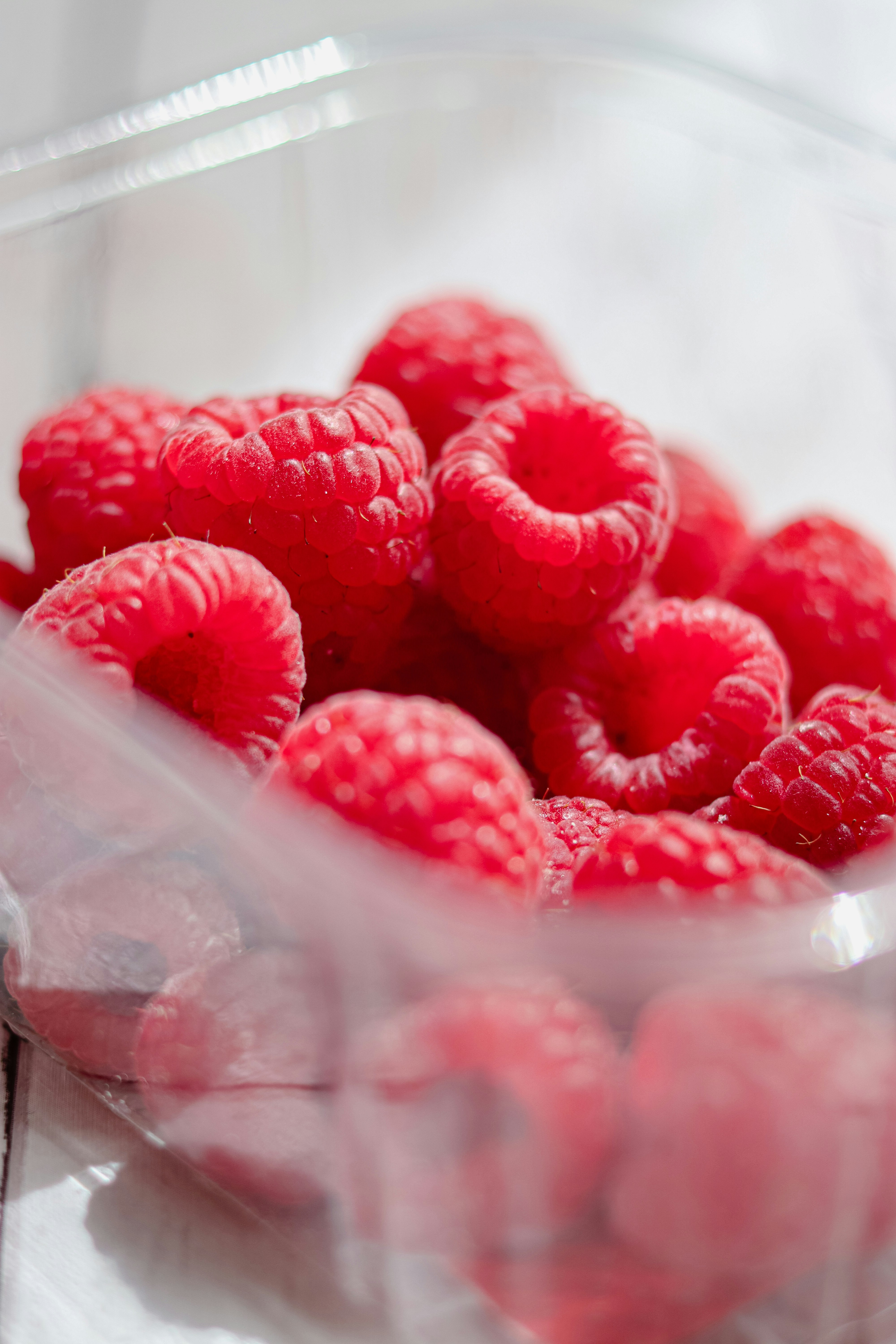 A plastic container filled with raspberries on top of a table photo ...