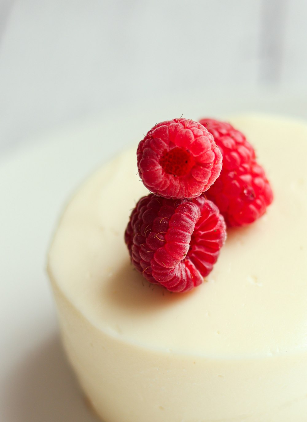 three raspberries on top of a white cake