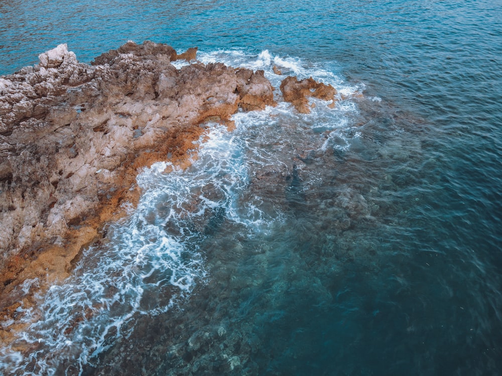 an aerial view of the ocean and rocks