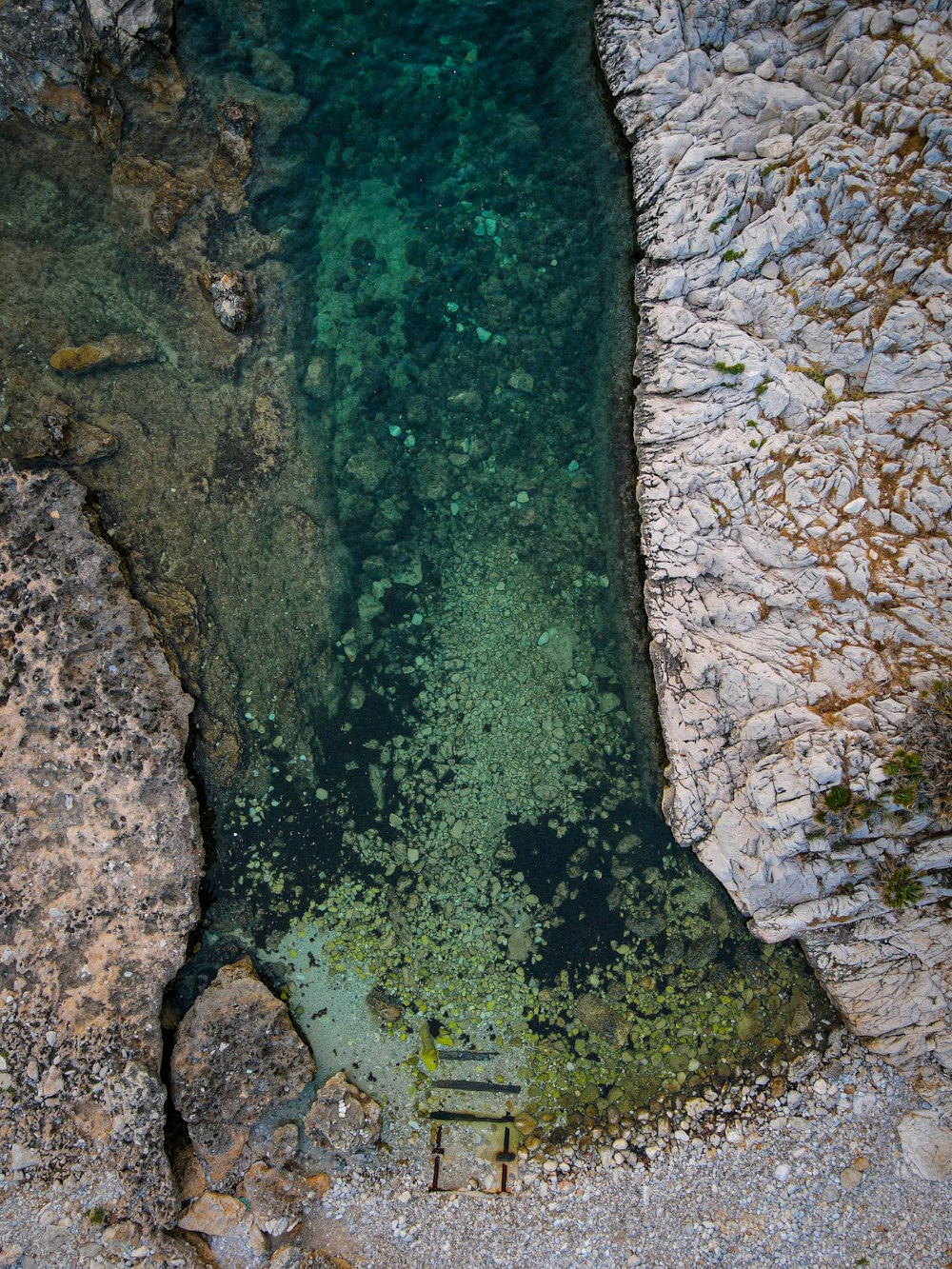 a body of water surrounded by rocks and grass