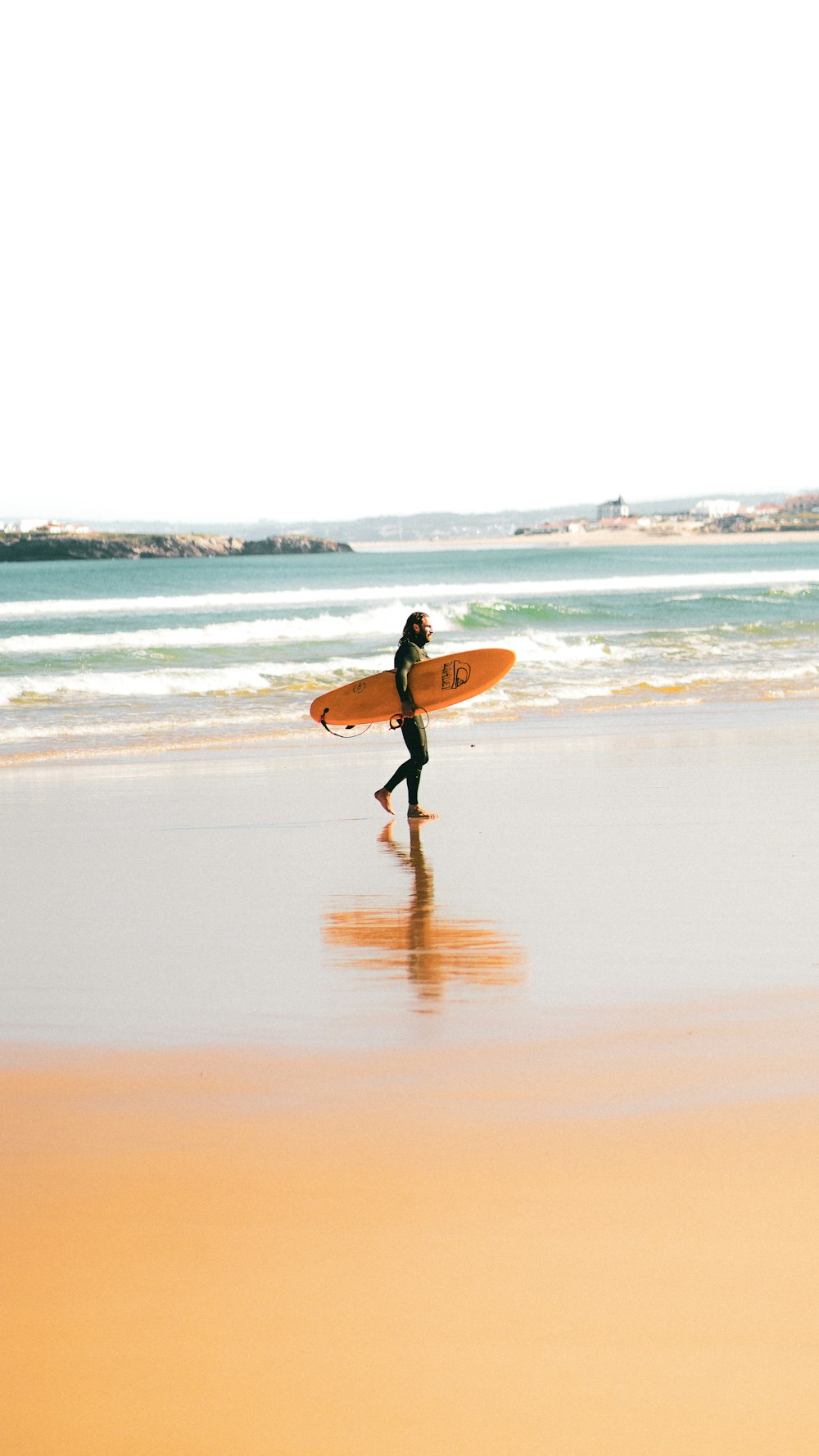 a person walking on a beach with a surfboard