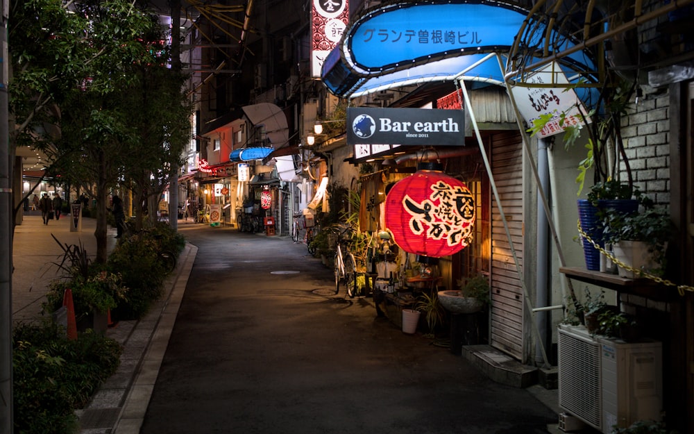 a narrow street at night with a sign for barearth