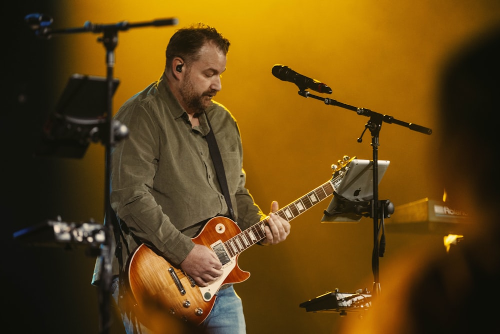 un uomo che suona una chitarra davanti a un microfono