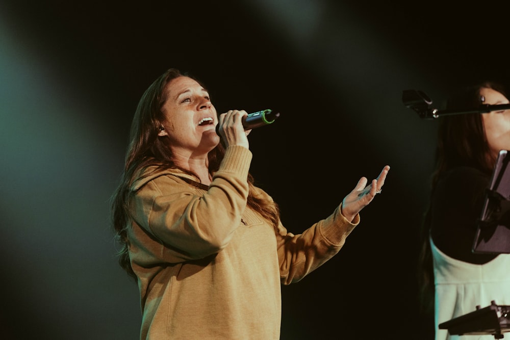 two women singing into microphones on stage