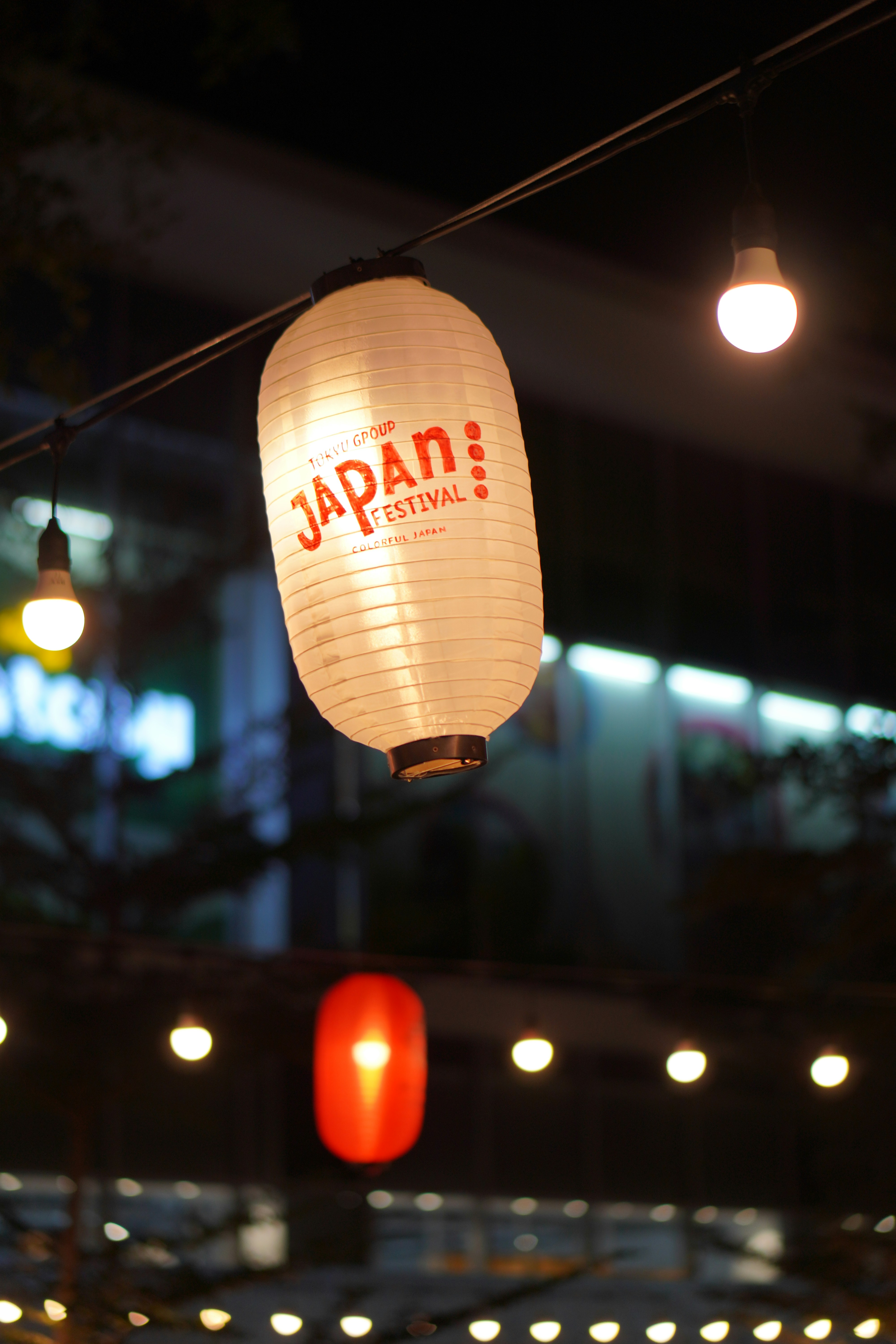 a white lantern hanging from a wire in front of a building