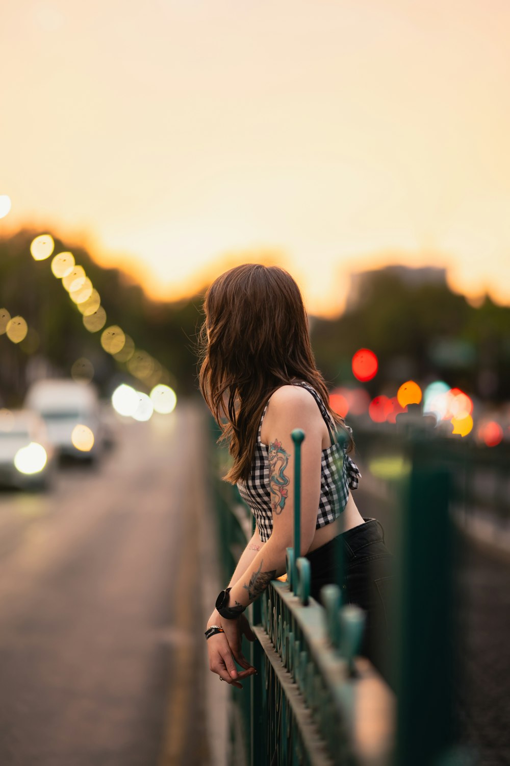 a woman leaning on a fence looking at the street