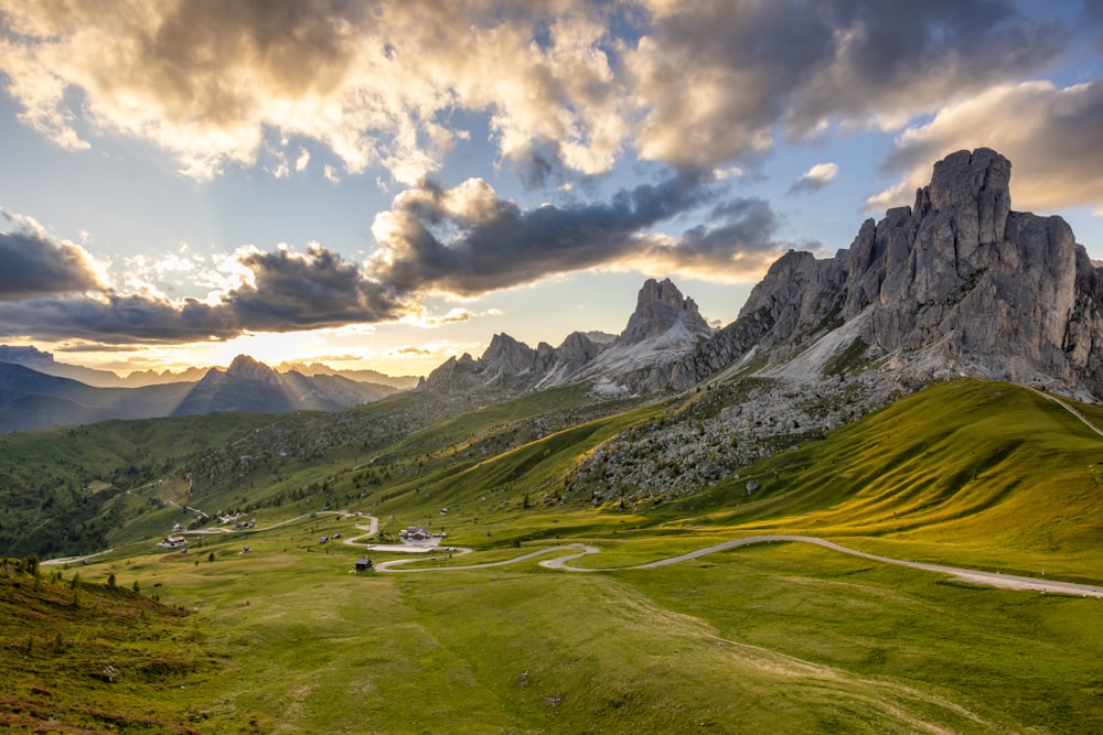 a scenic view of a mountain range with a winding road in the foreground