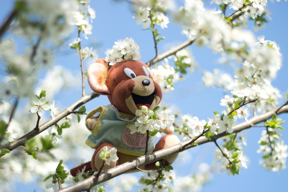 a stuffed animal sitting on a branch of a tree