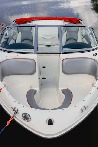 a white boat with a red seat is docked in the water