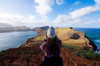 a woman standing on top of a cliff overlooking the ocean