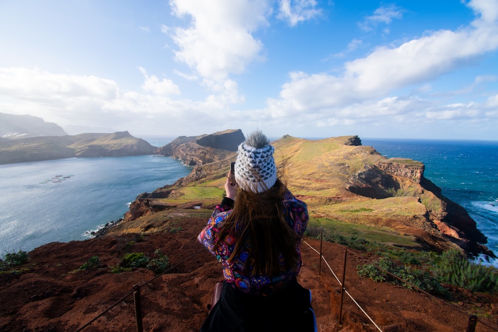 a woman standing on top of a cliff overlooking the ocean