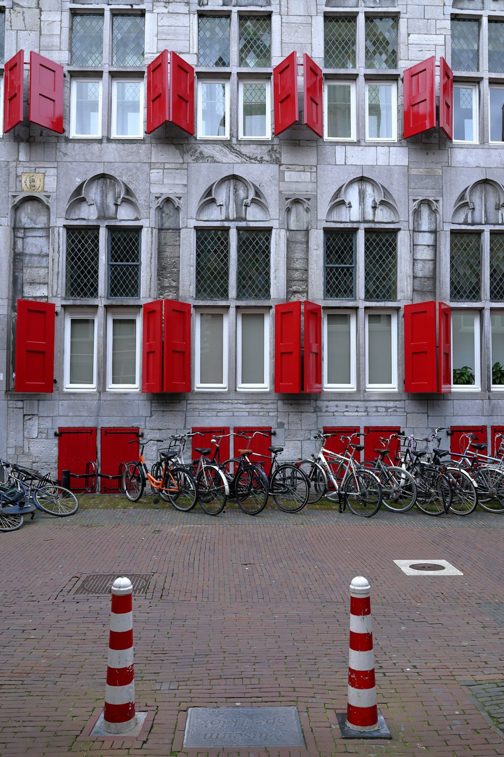 a row of bikes parked in front of a building with red shutters