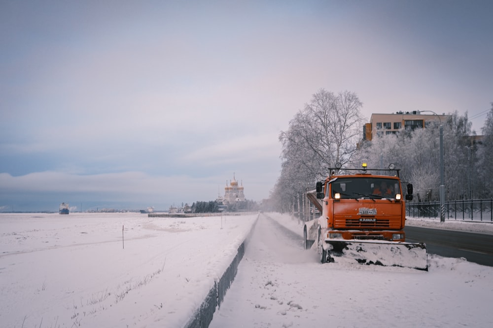 a snow plow is driving down a snowy road