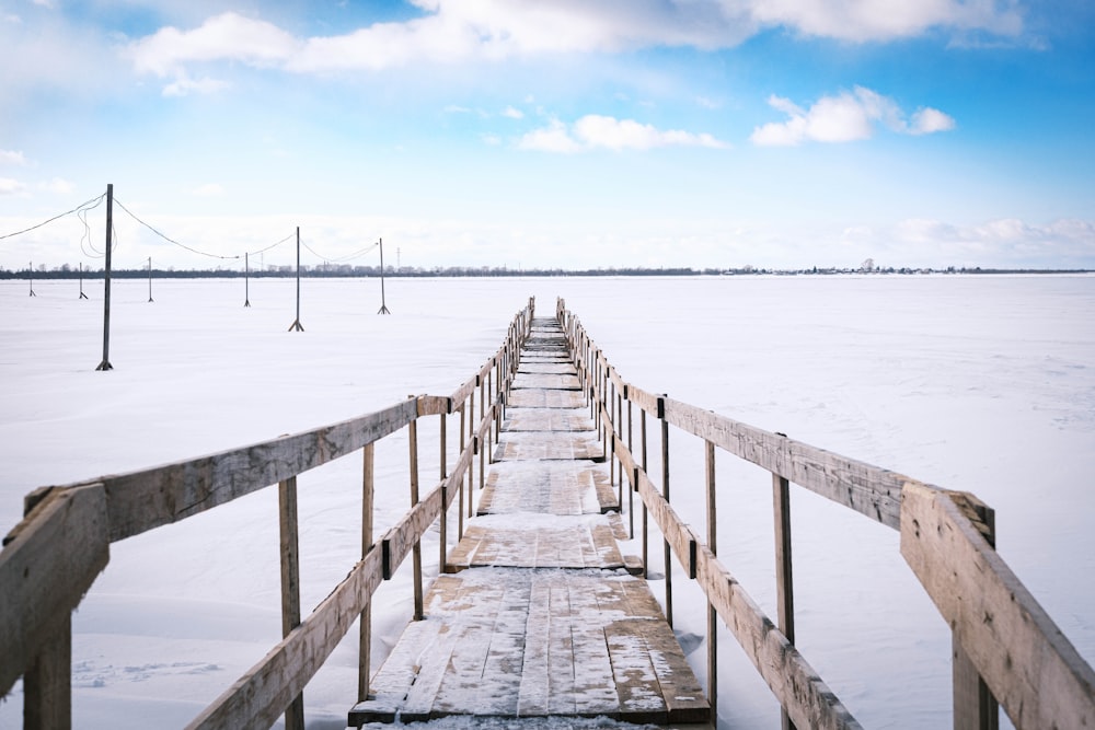 a long wooden pier in the middle of a frozen lake