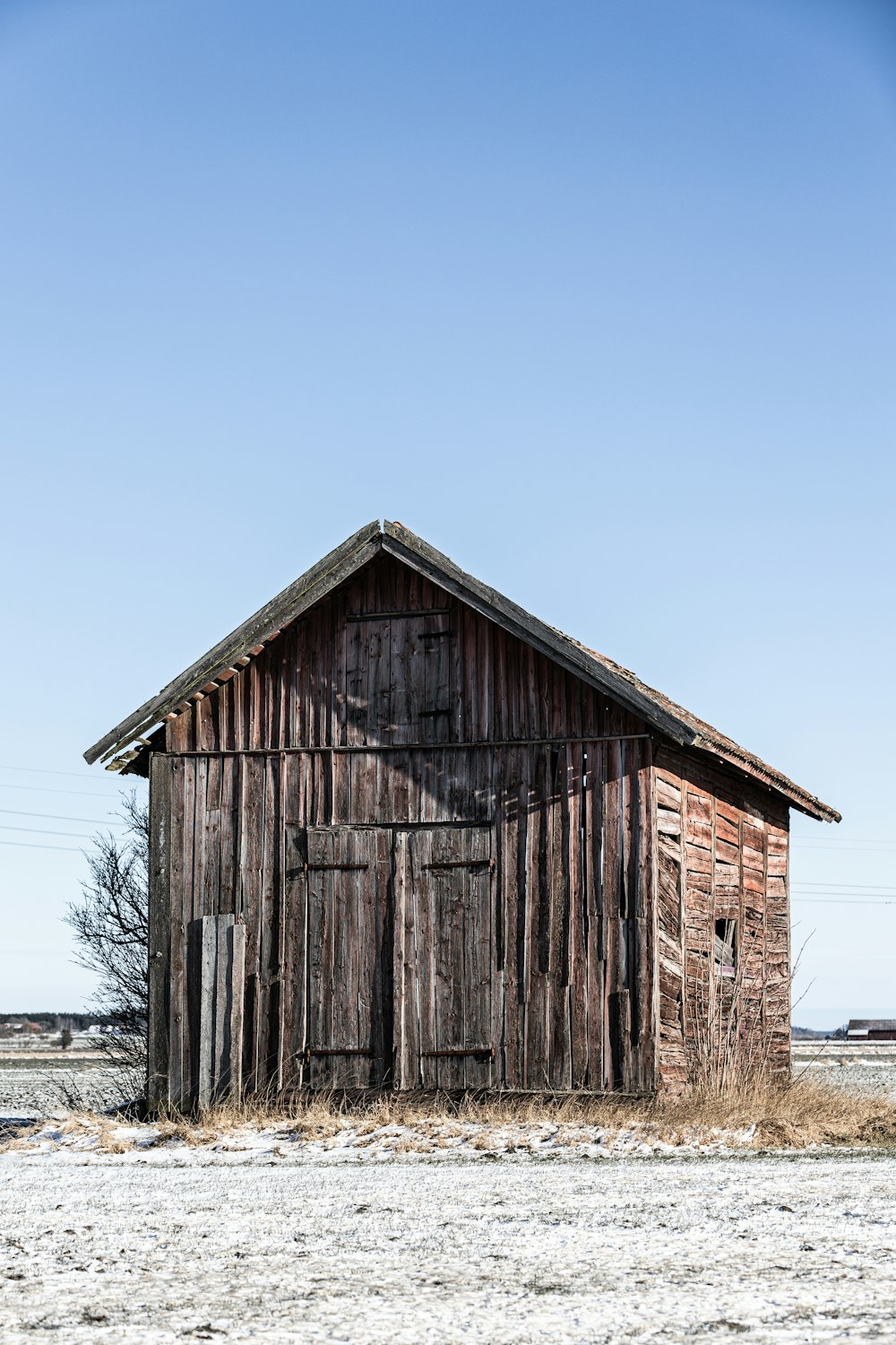 an old wooden building in a field with a sky background