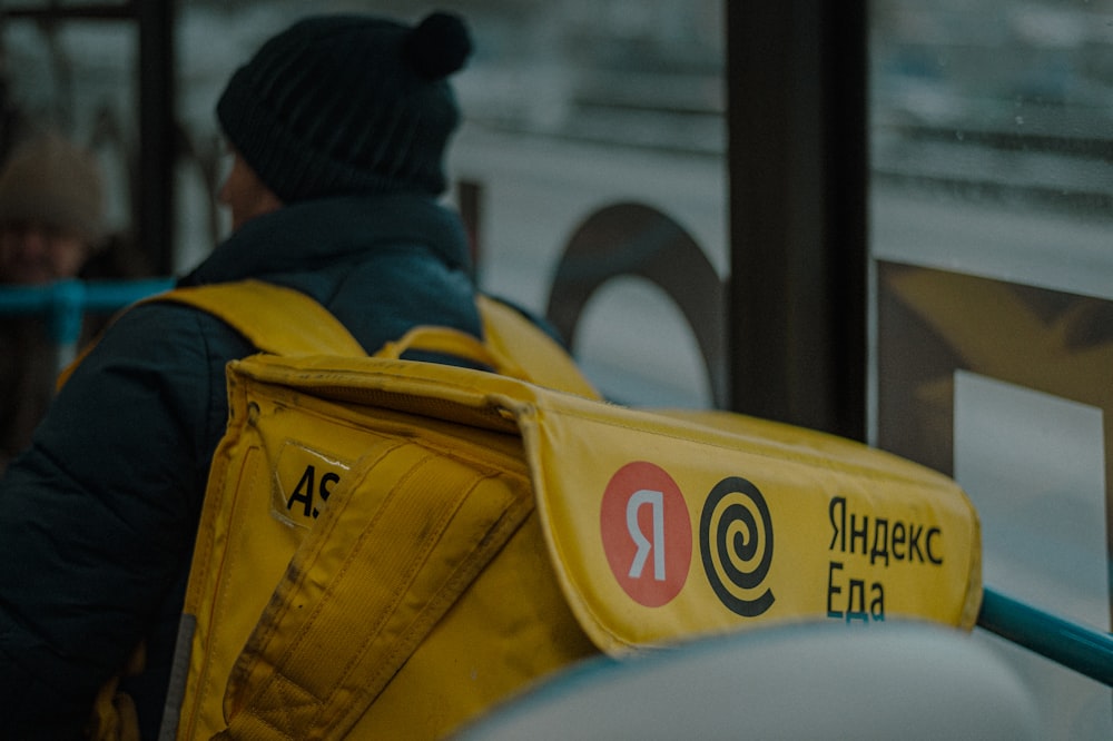 una persona che indossa uno zaino giallo seduta su un autobus