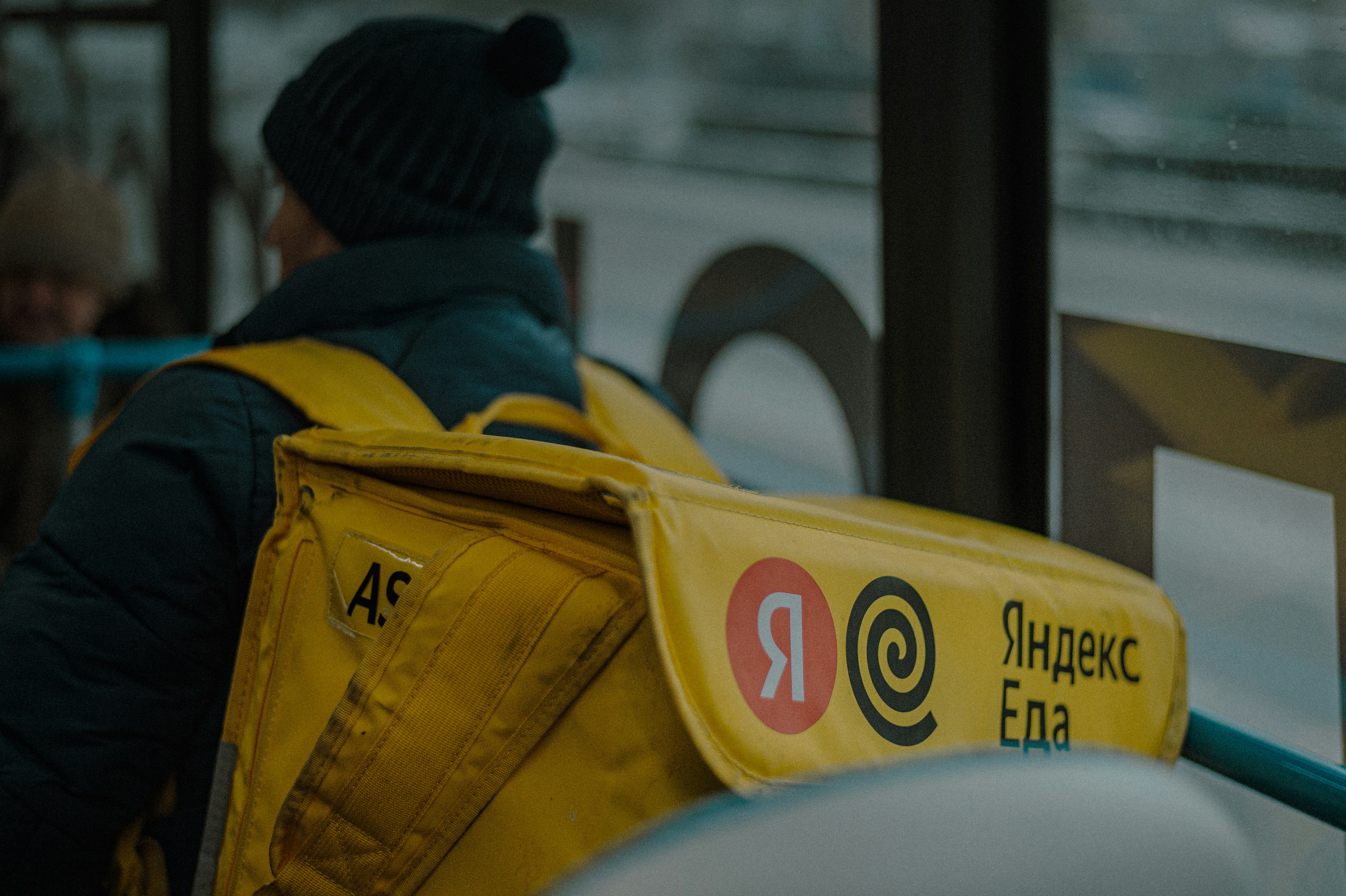 Courier with a bag of Yandex Food rides in public transportation.