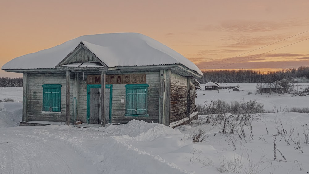 a small wooden building sitting in the middle of a snow covered field