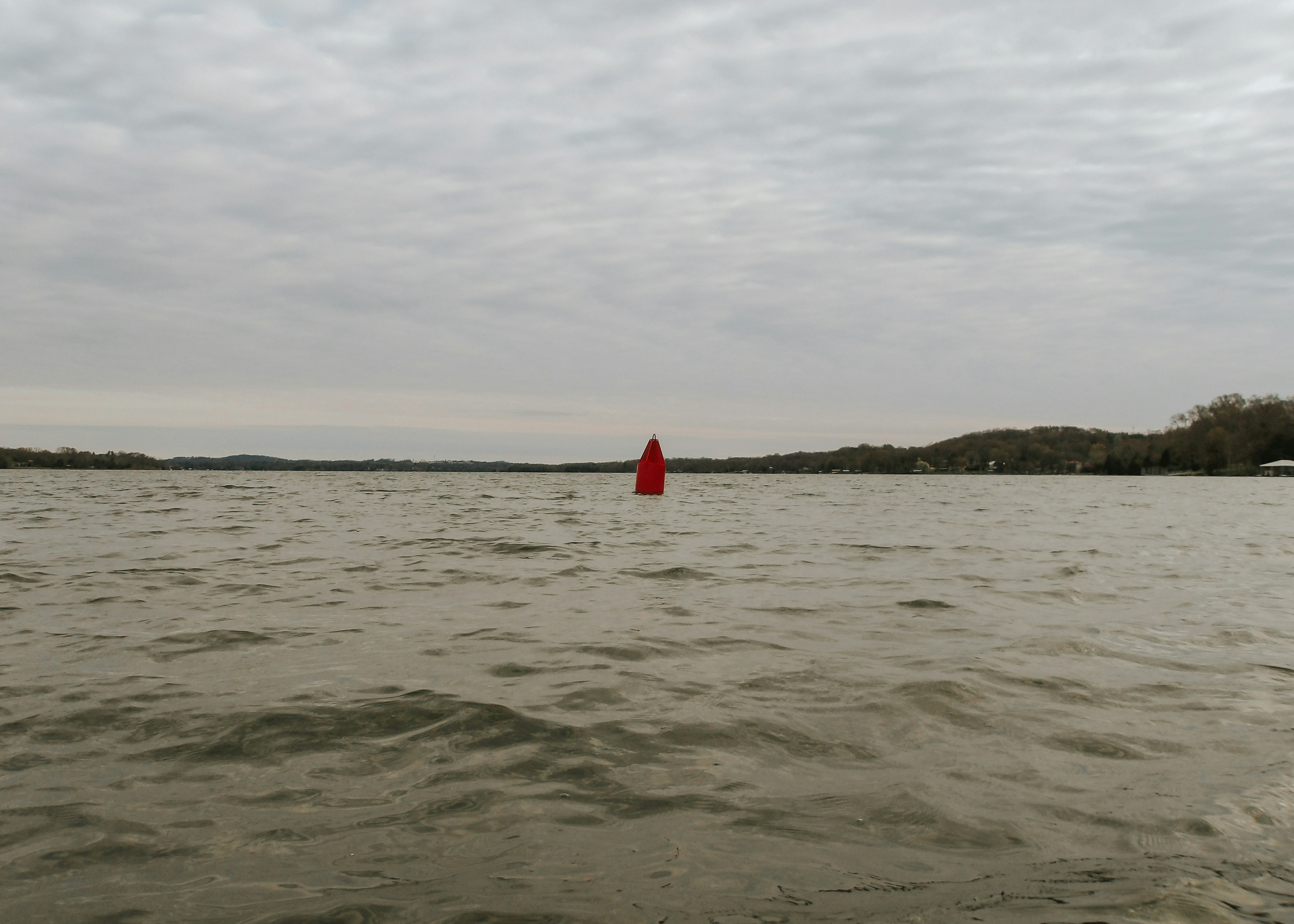 a body of water with a red buoy in the middle of it